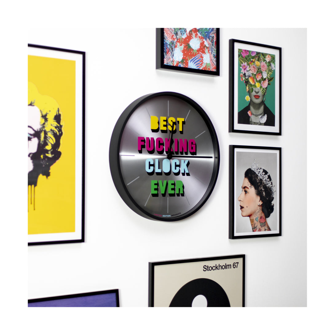 Skew view of the Spun aluminium and silicone black, limited edition slogan wall clock by Newgate World, on a gallery wall