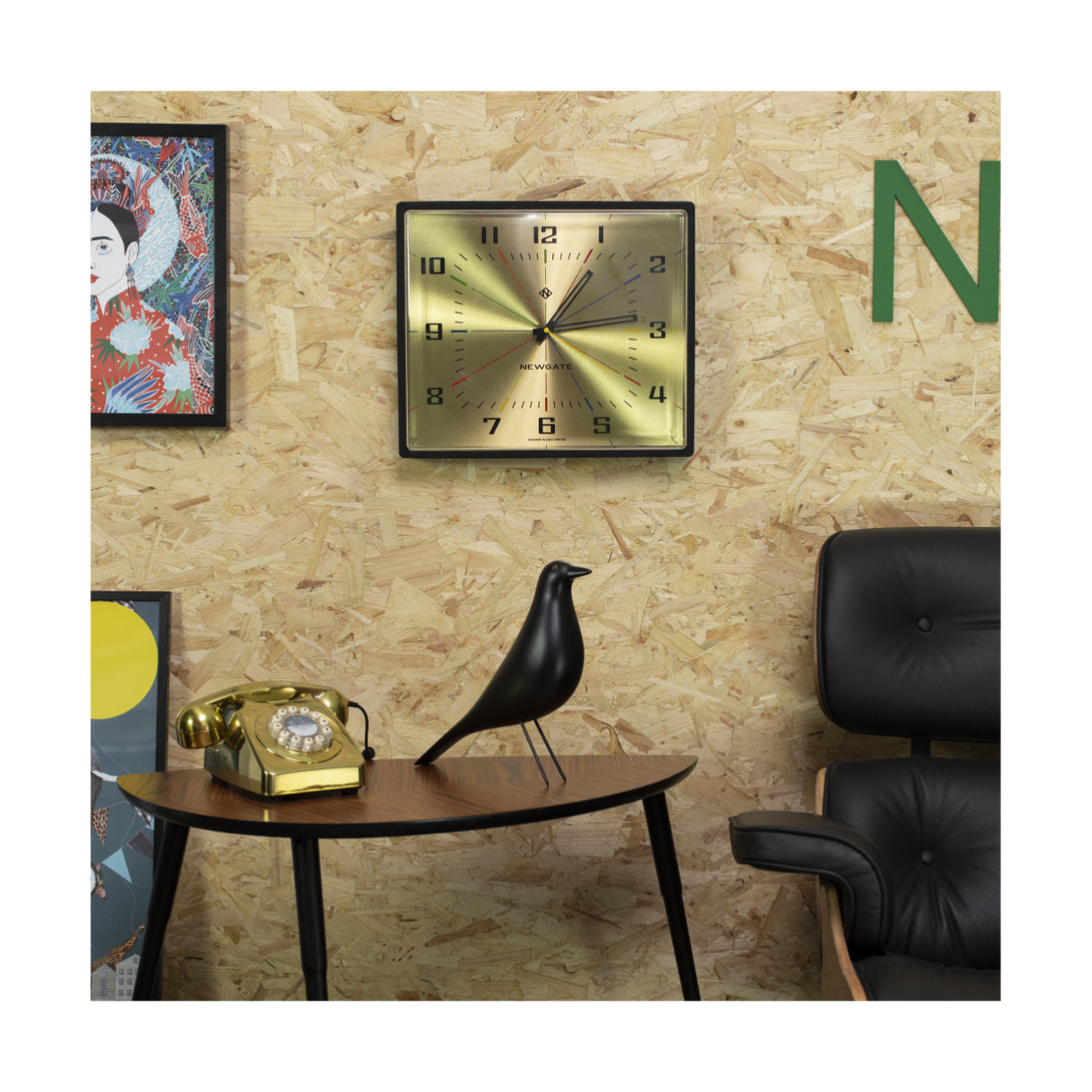 Room setting including the rectangular Box Office wall clock by Newgate World in spun brass with a 3D lens and a black case