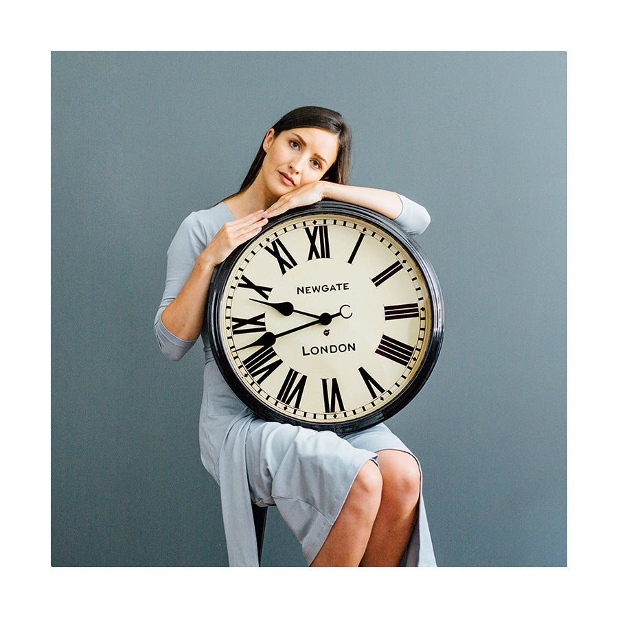 Classic large Roman Numeral Battersby wall clock by Newgate Clocks being held by a woman